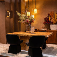 "Stylish black chairs around a warm-toned marble table, accented by earthy floral arrangements and soft lighting."