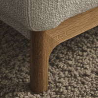 Light gray textured fabric with natural wood leg accent on a soft, neutral-toned rug. Minimalistic and modern design.