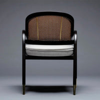 Elegant black wooden chair featuring a brown woven back and gray cushion with gold accents. Perfect for modern decor.