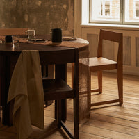 Wooden dining table with natural tones, a beige linen napkin, and simple, clean-lined furniture accents.