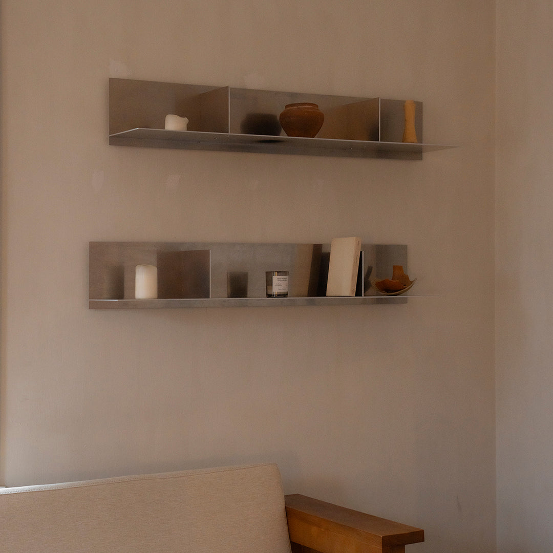 Sleek metal wall shelves on a soft neutral wall, showcasing earthy tones and minimalistic designs.