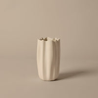 White textured vase with a wavy pattern, featuring unique fluted edges against a beige background.