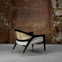 Elegant black and white chair with rattan accents and gold legs, showcasing a modern, minimalist design.