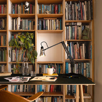 Stylish black desk with minimalist design, surrounded by colorful books and a green plant for a vibrant workspace.