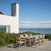 Outdoor dining set featuring natural wood tones and a minimalistic design against a vibrant coastal backdrop.