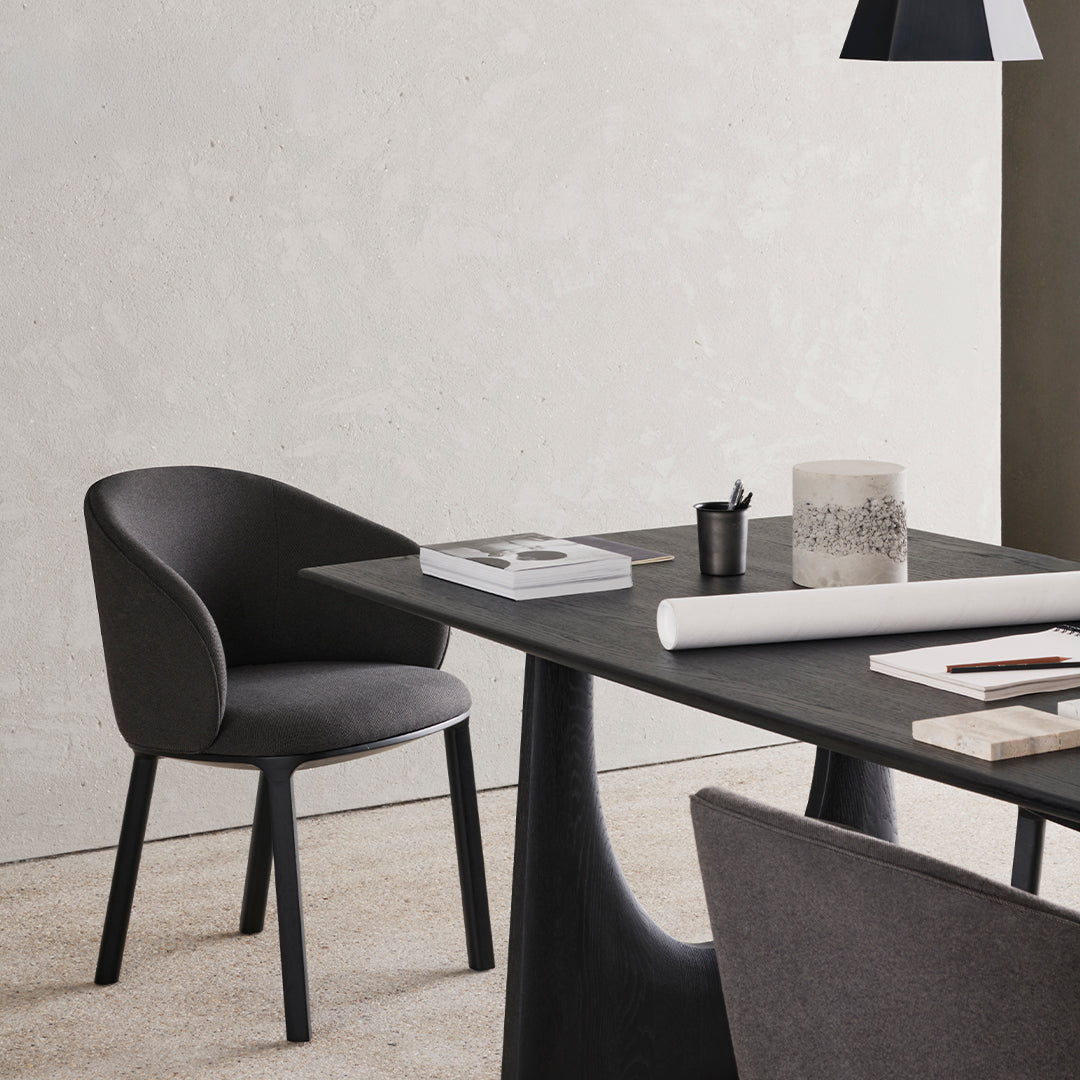Stylish black chair and table against a textured light gray wall, featuring muted tones and elegant modern patterns.