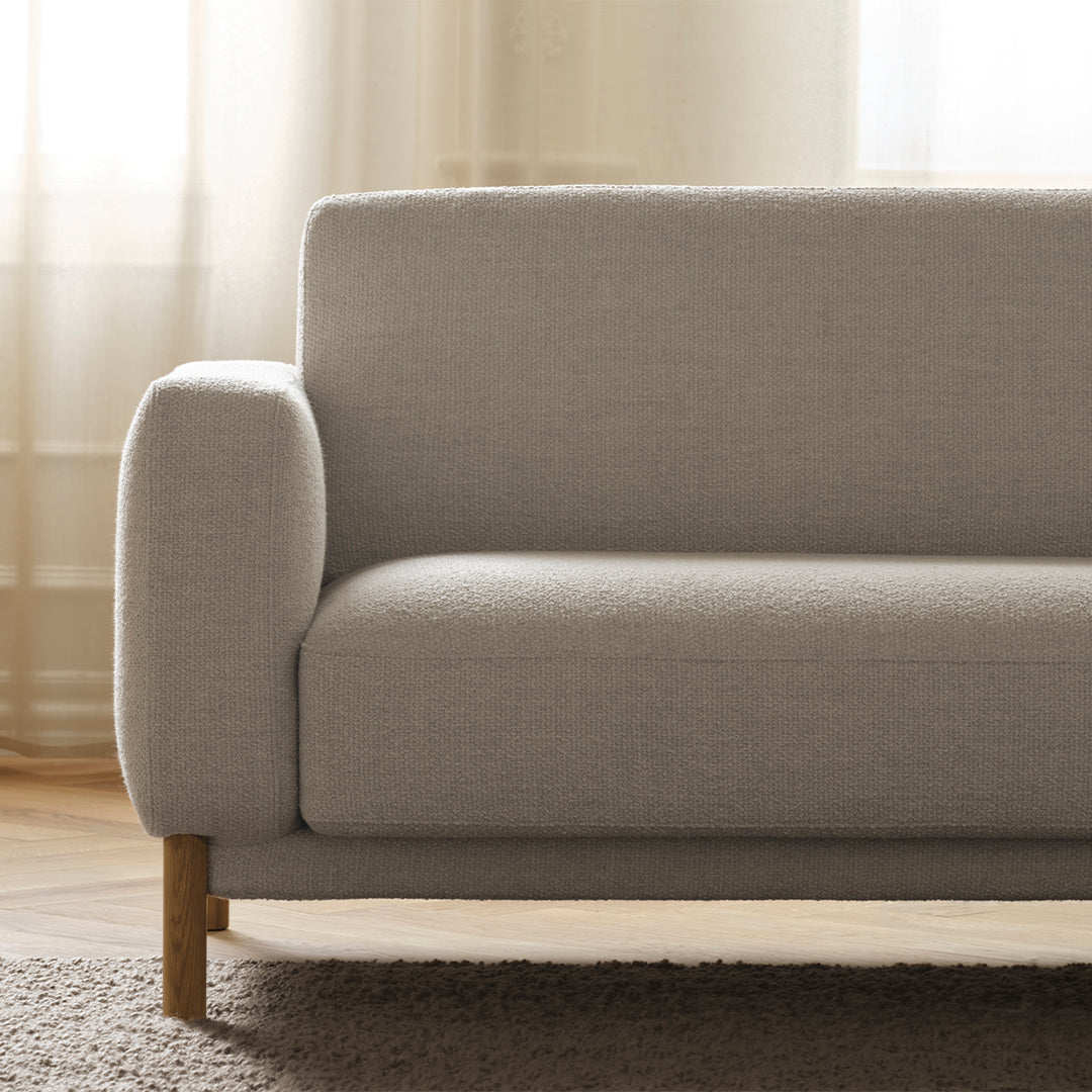 Light gray textured fabric sofa with clean lines and wooden legs, set in a softly lit room.