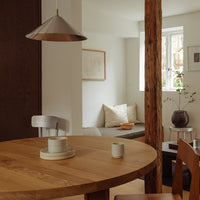 Wooden table with light tones, metallic accents, and soft beige textiles in a cozy, modern interior setting.