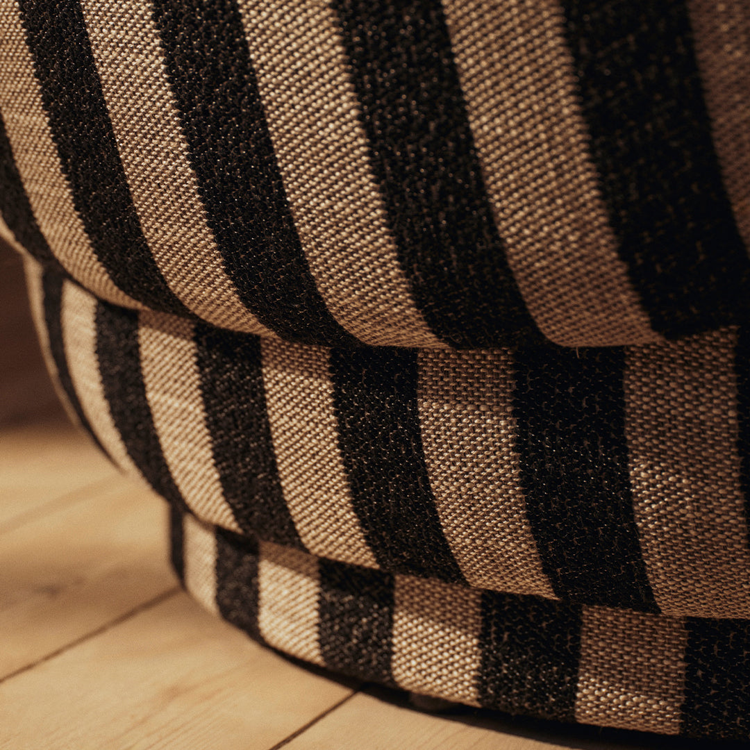 Black and cream striped fabric close-up, showcasing a textured pattern on a round cushion.