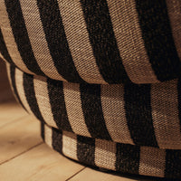 Black and cream striped fabric close-up, showcasing a textured pattern on a round cushion.