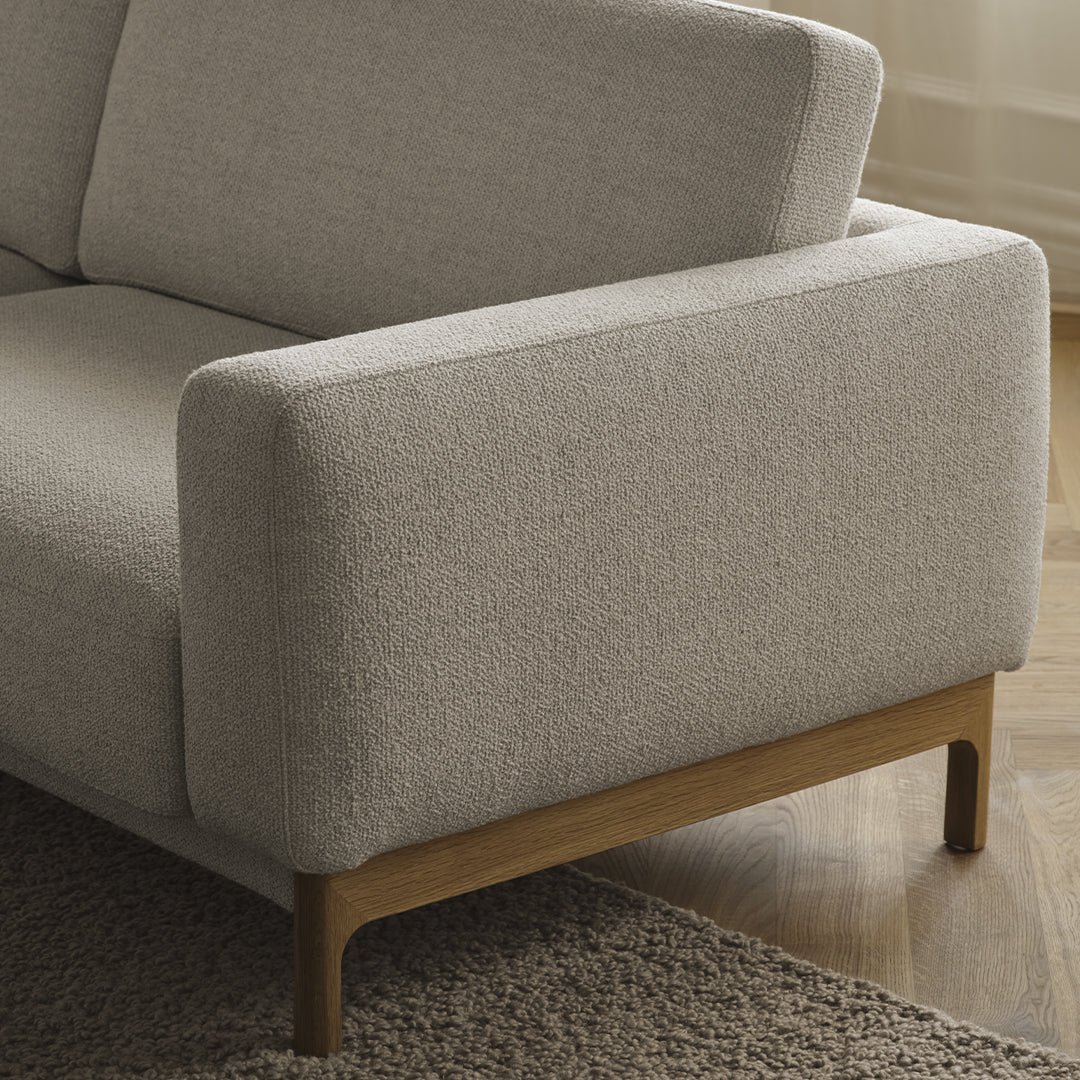 Light gray sofa with a textured fabric and natural wood legs, featuring a minimalist design and cozy appeal.