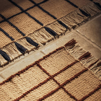 Natural woven rugs featuring beige and brown patterns with navy accents and fringe edges for textured appeal.