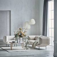 Light beige modern sofa with soft curved shapes, complemented by neutral gray curtains and a pale wooden floor.
