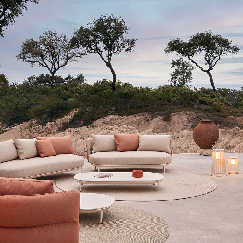 Cozy outdoor seating in soft beige and warm terracotta hues, featuring a smooth circular coffee table and round rug.