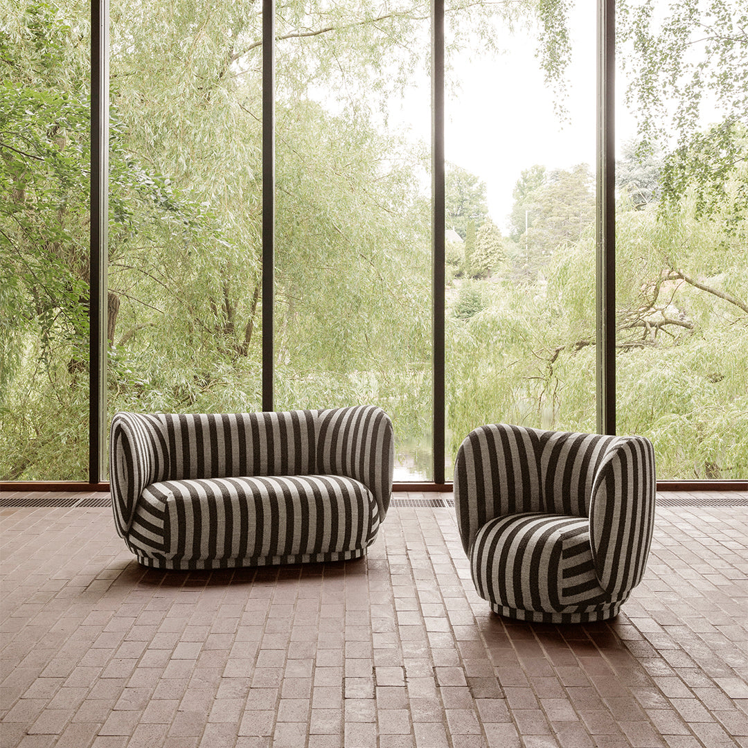 Striped black and white sofa and chair set against a backdrop of lush greenery and large windows.