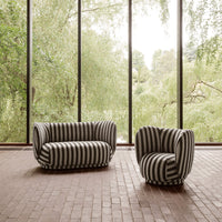 Striped black and white sofa and chair set against a backdrop of lush greenery and large windows.