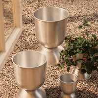 "Set of three sleek silver metal planters with smooth, shiny finishes and minimalist design."