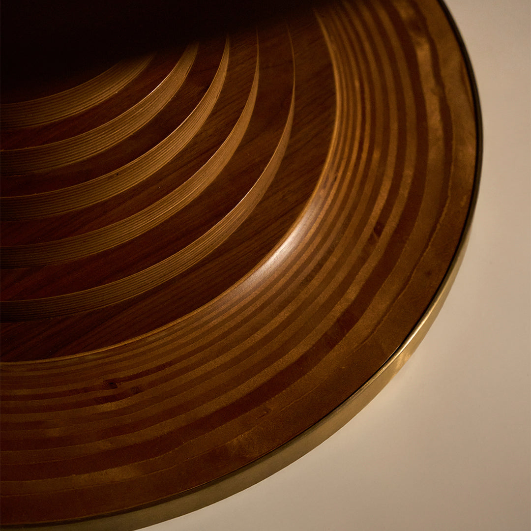Brown wooden bowl with a spiral striped pattern, featuring warm tones and a glossy finish. Ideal for decor or serving.