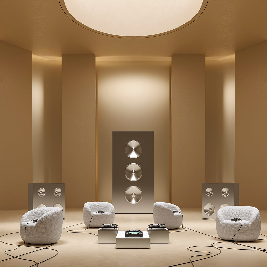 Modern living room with beige walls, white circular chairs, and sleek metallic speakers, creating a minimalist aesthetic.
