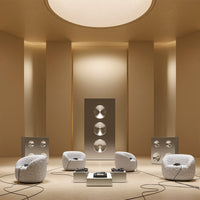 Modern living room with beige walls, white circular chairs, and sleek metallic speakers, creating a minimalist aesthetic.