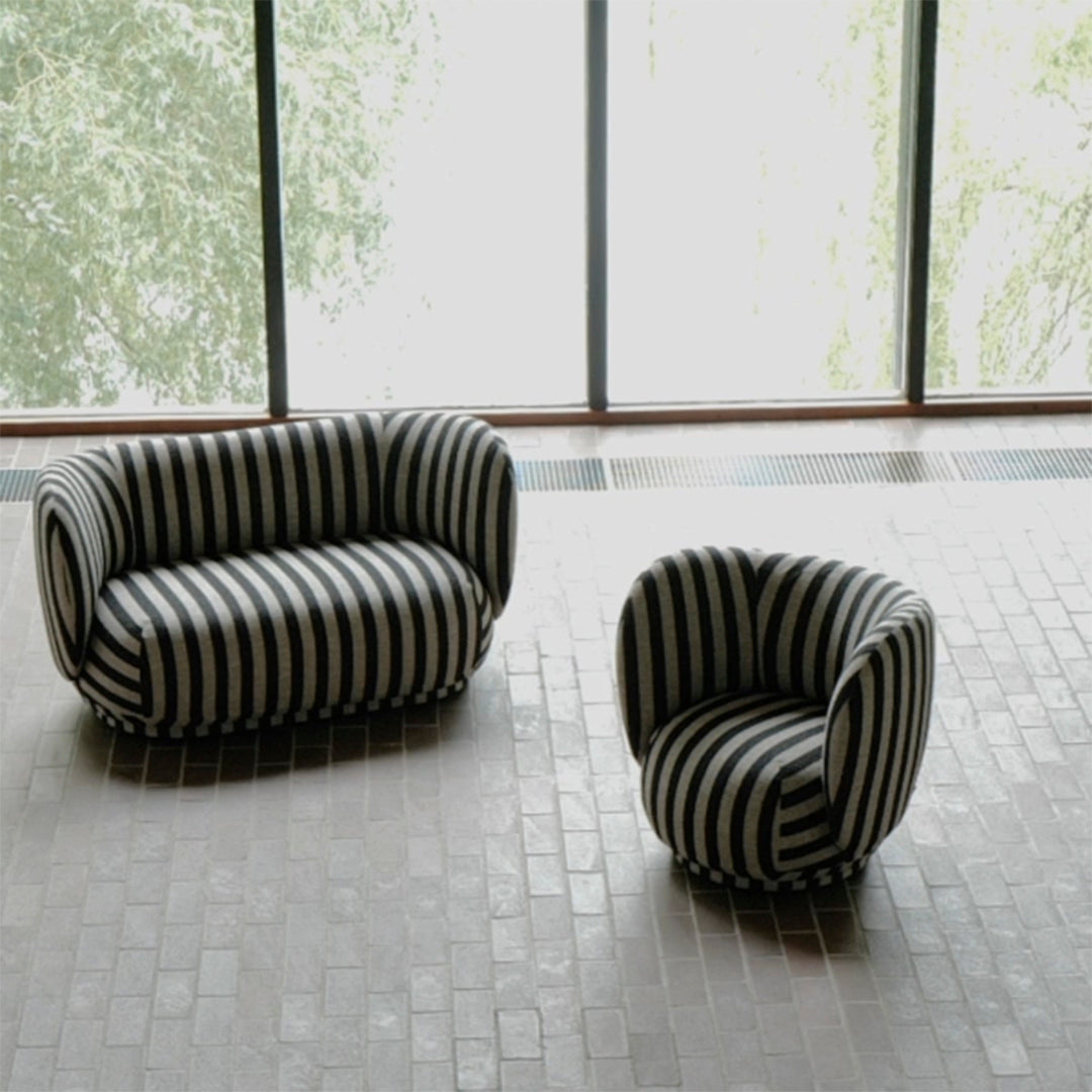 "Black and white striped sofa and chair set with a modern design on a textured floor."