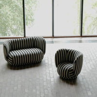 "Black and white striped sofa and chair set with a modern design on a textured floor."