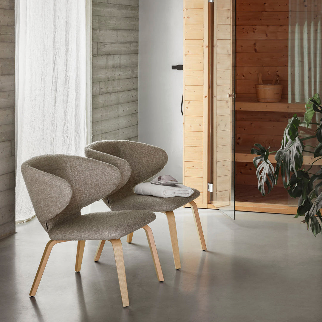 Neutral beige chairs with soft curves and light wooden legs, set against a modern, minimalist interior.