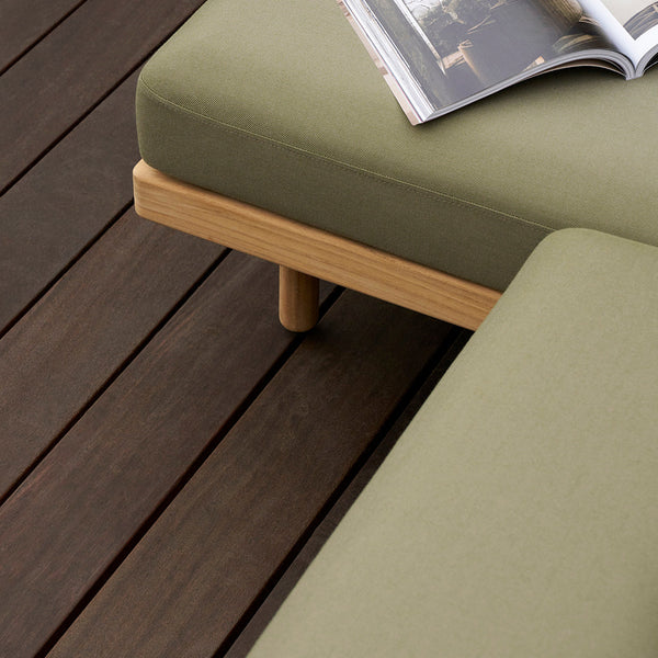 Olive green cushions with a textured finish, paired with a light wood frame, on dark wooden flooring.