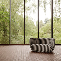 Black and white striped sofa against a backdrop of greenery and large windows. Modern and stylish design.