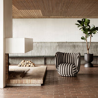 Black and white striped armchair in a modern interior with earthy tones and natural textures.