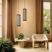 "Black patterned pendant lights against warm beige walls, paired with a neutral cream chair and natural greenery."