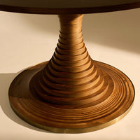 Wooden table base with spiral patterns in warm brown tones and a shiny gold trim.