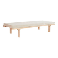 Light-colored, minimalistic wooden bed frame with a simple, solid cushion in a neutral beige hue.