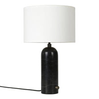 Black marble lamp base with a smooth, rounded design and a white drum shade for a modern touch.