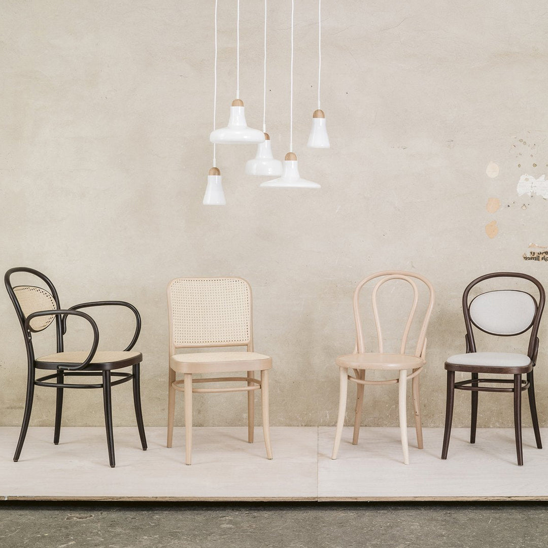 Set of four stylish chairs in black, beige, and brown against a textured gray backdrop. Modern design with simple lines.