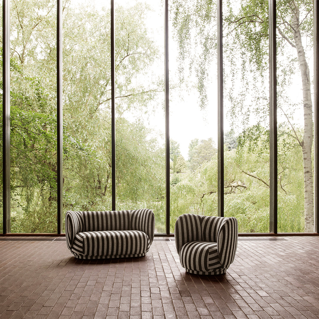 Black and white striped sofa and chair set against a backdrop of lush greenery and natural light.