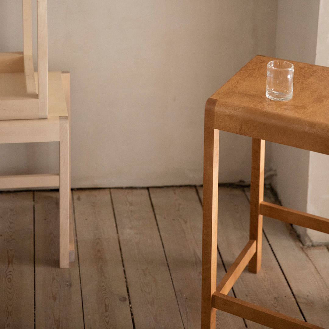 Light wooden bar table with a smooth finish, featuring natural grain patterns, paired with a light-colored chair.