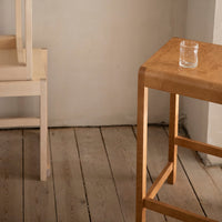 Light wooden bar table with a smooth finish, featuring natural grain patterns, paired with a light-colored chair.