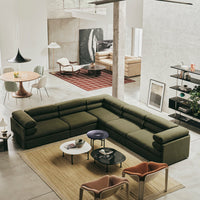 Olive green sectional sofa with a textured fabric, paired with colorful accent chairs and a neutral rug in a modern living space.