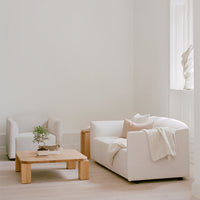 "Neutral-toned living room featuring a white sofa, beige accents, and a natural wood coffee table."