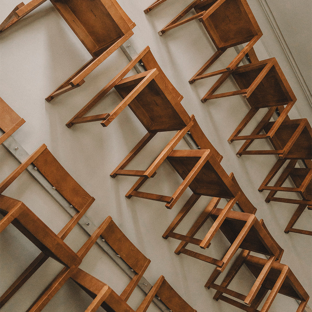 Wall-mounted wooden chairs with a rich brown finish, showcasing a minimalist design and unique overlapping pattern.