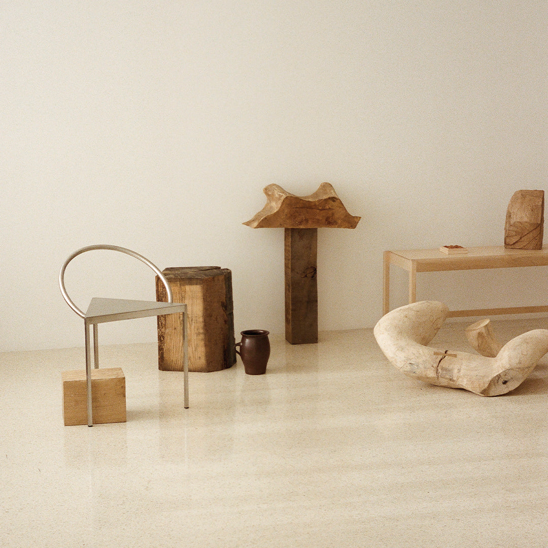 Minimalist room featuring earthy tones, natural wood textures, sleek metallic accents, and organic shapes.