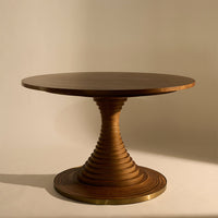 Round wooden table with a spiral-patterned pedestal in rich brown tones against a neutral background.