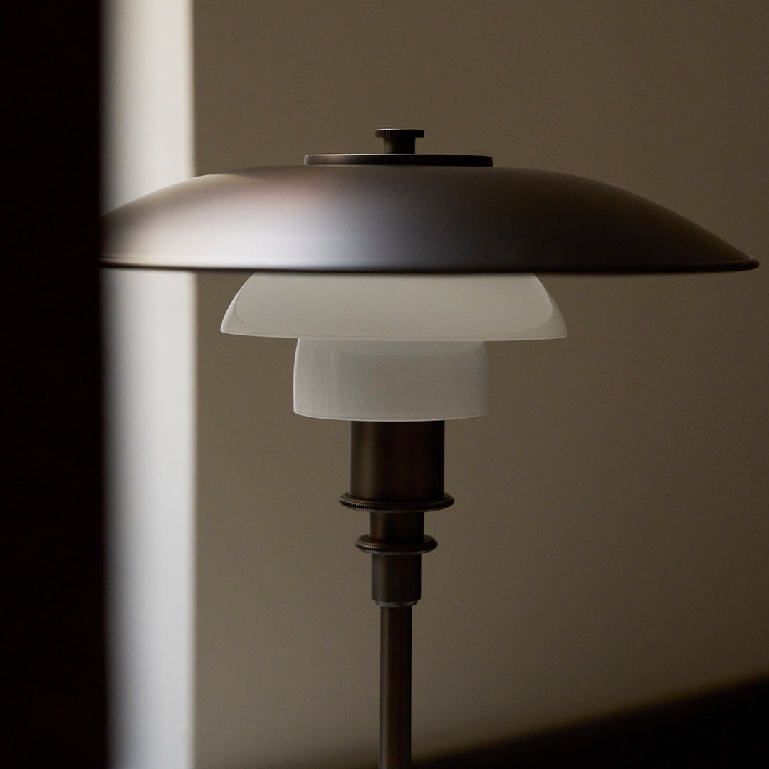 Sleek metallic lamp with a matte bronze finish and frosted glass shade, featuring a minimalist, modern design.