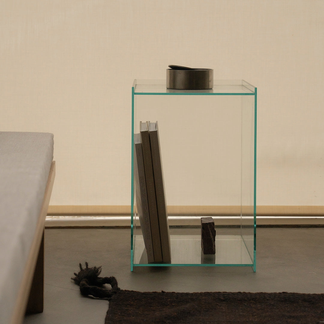 Clear glass side table with teal accents, featuring a minimalistic design and sleek lines against a neutral backdrop.