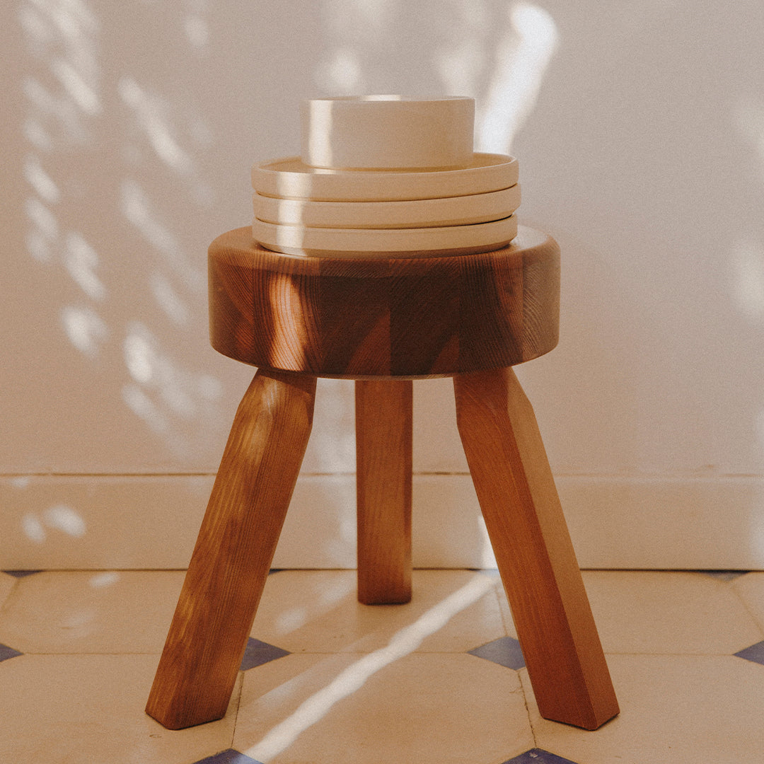 Wooden stool with a geometric pattern, featuring a warm brown finish and light-colored circular bowls on top.