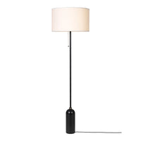 Black floor lamp with a simple white drum shade, minimalist design ideal for modern decor.