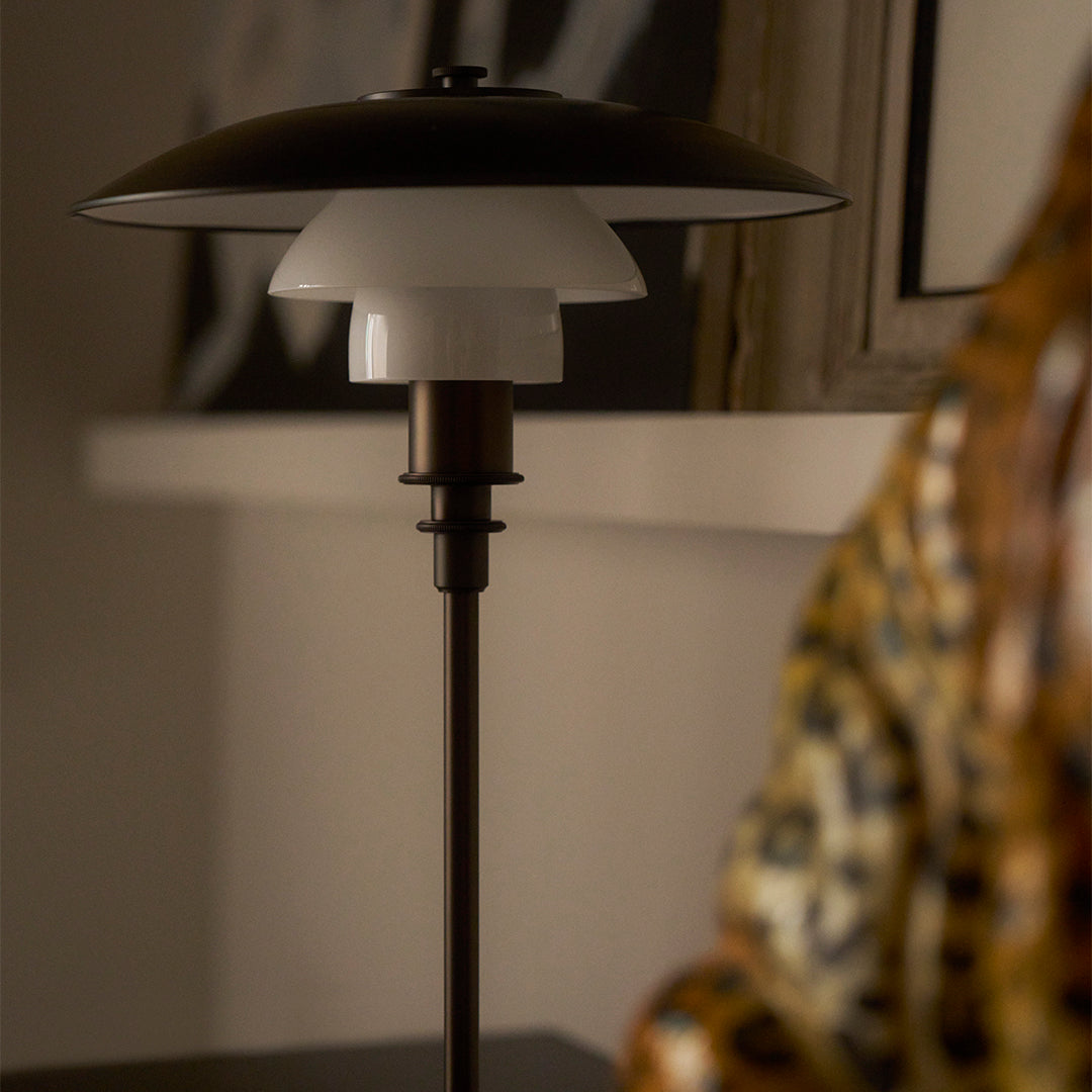 Modern black and white lamp with sleek lines and subtle matte finish, set against a warm, earthy background.