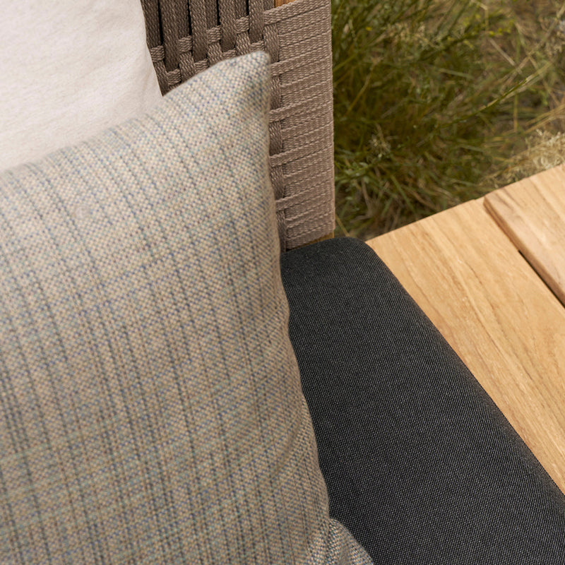 Beige plaid cushion with subtle blue accents on a dark gray seating surface. Natural textures enhance outdoor decor.
