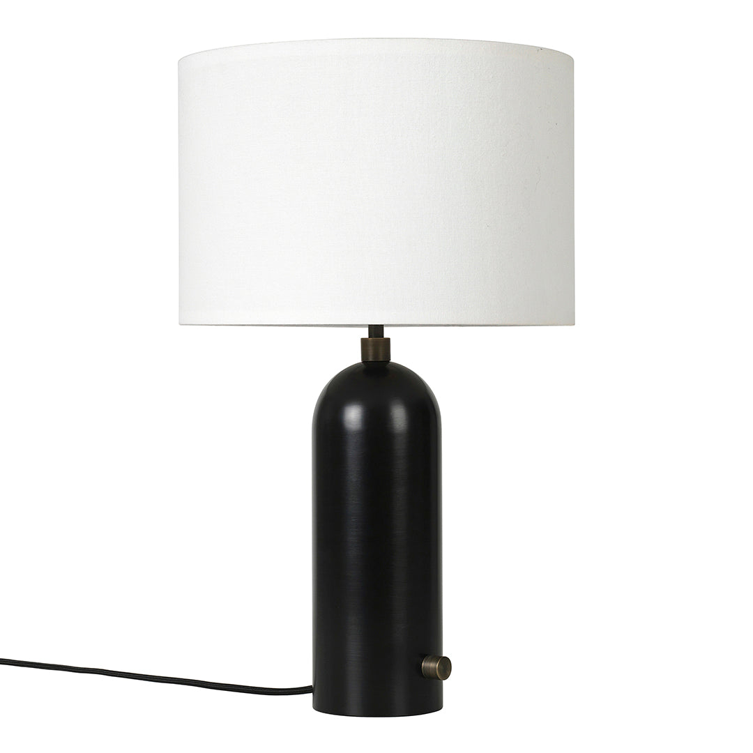 Black cylindrical lamp base with a white round shade and gold accent. Modern, minimalist design for versatile decor.